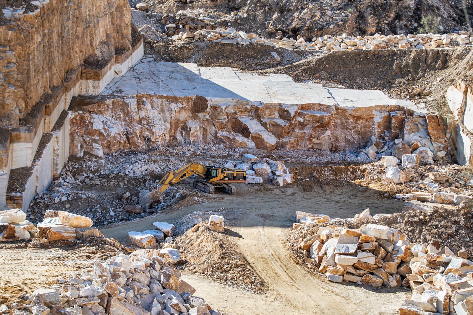 Excavadora trabajando en una cantera de piedra durante la extracción de materias primas, primera etapa del ciclo de vida de un producto