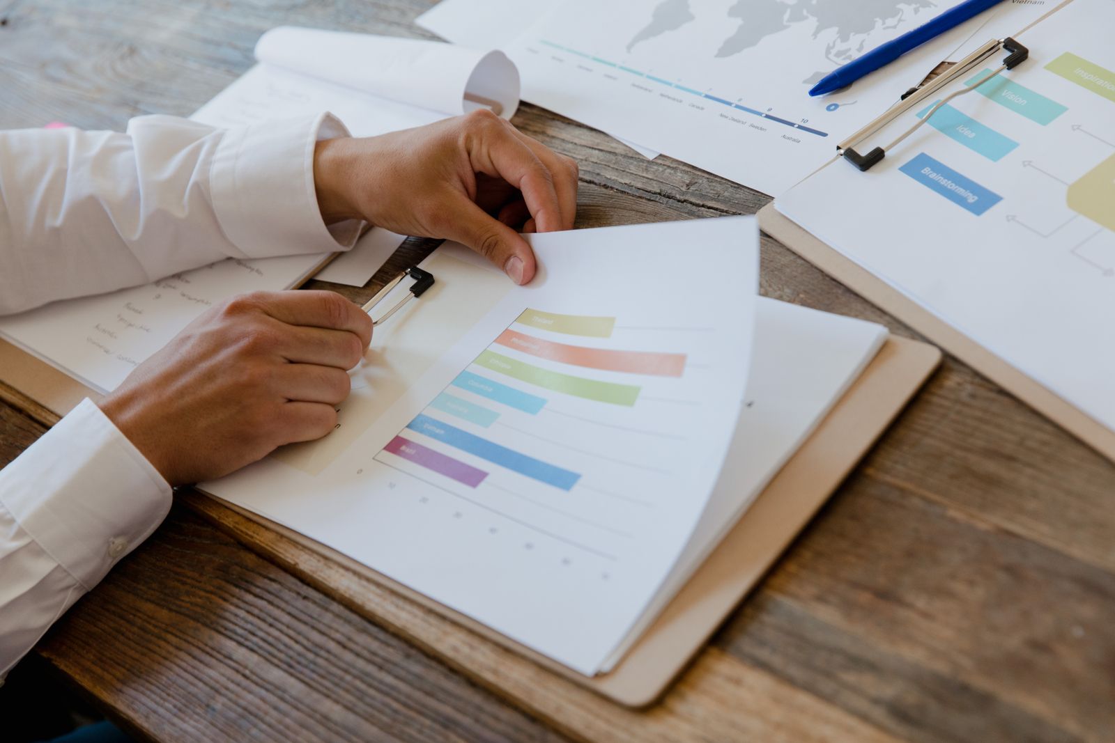 Manos revisando un informe con gráficos y datos sobre una mesa de madera, que ilustra una declaración ambiental de producto verificada