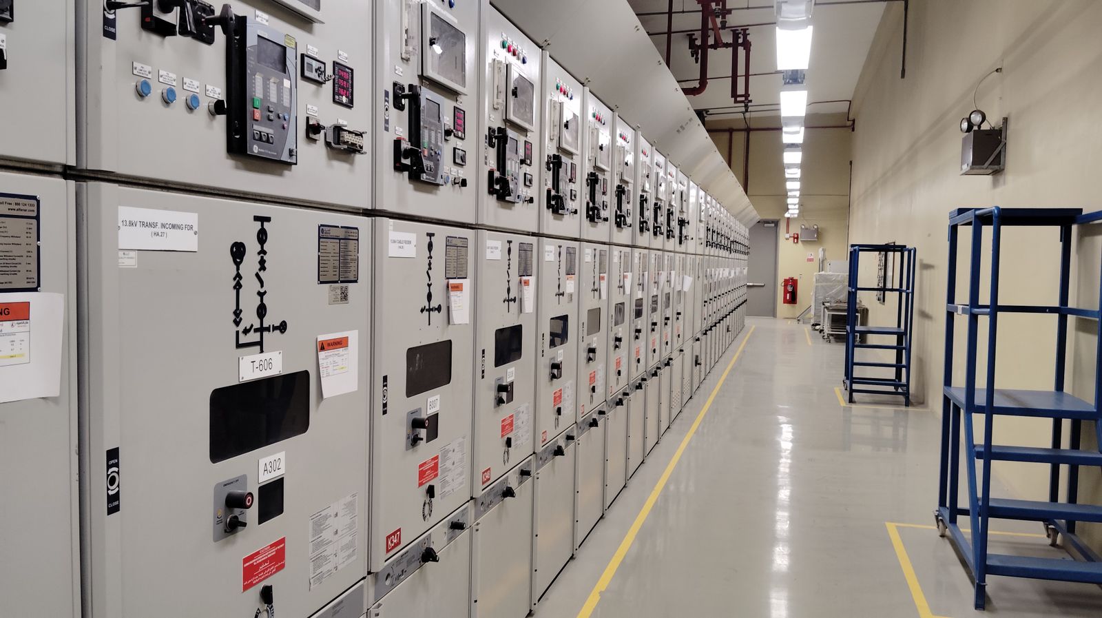 Sala de celdas electricas de media tension (linea de cuadros/switchgear) en un pasillo de 