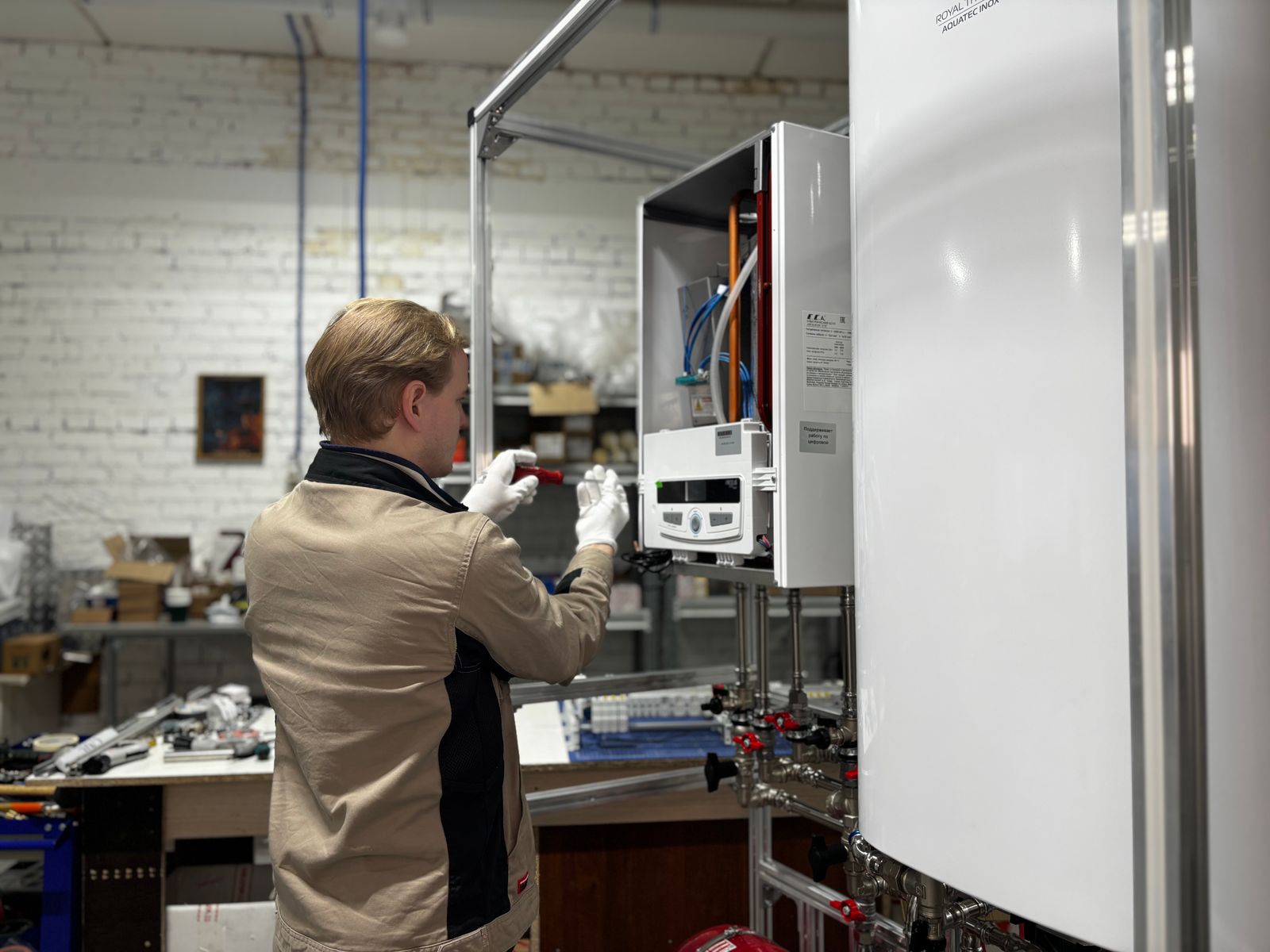 Técnico instalando una caldera industrial con su cuadro de control