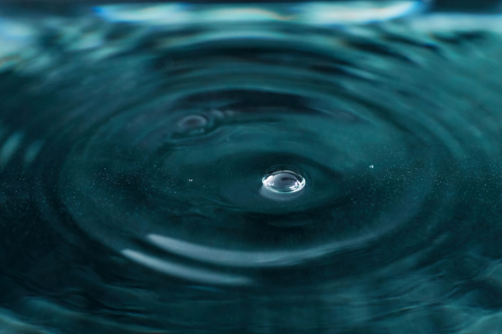 Primer plano de una gota de agua formando ondas al caer sobre la superficie