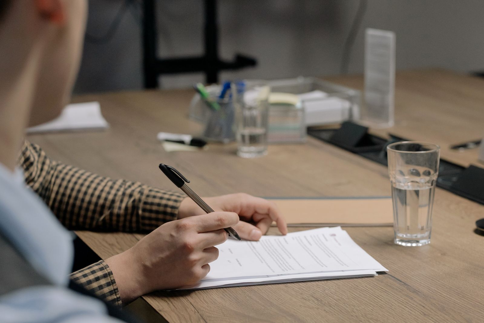Profesional revisando y firmando documentación sobre una mesa en una oficina