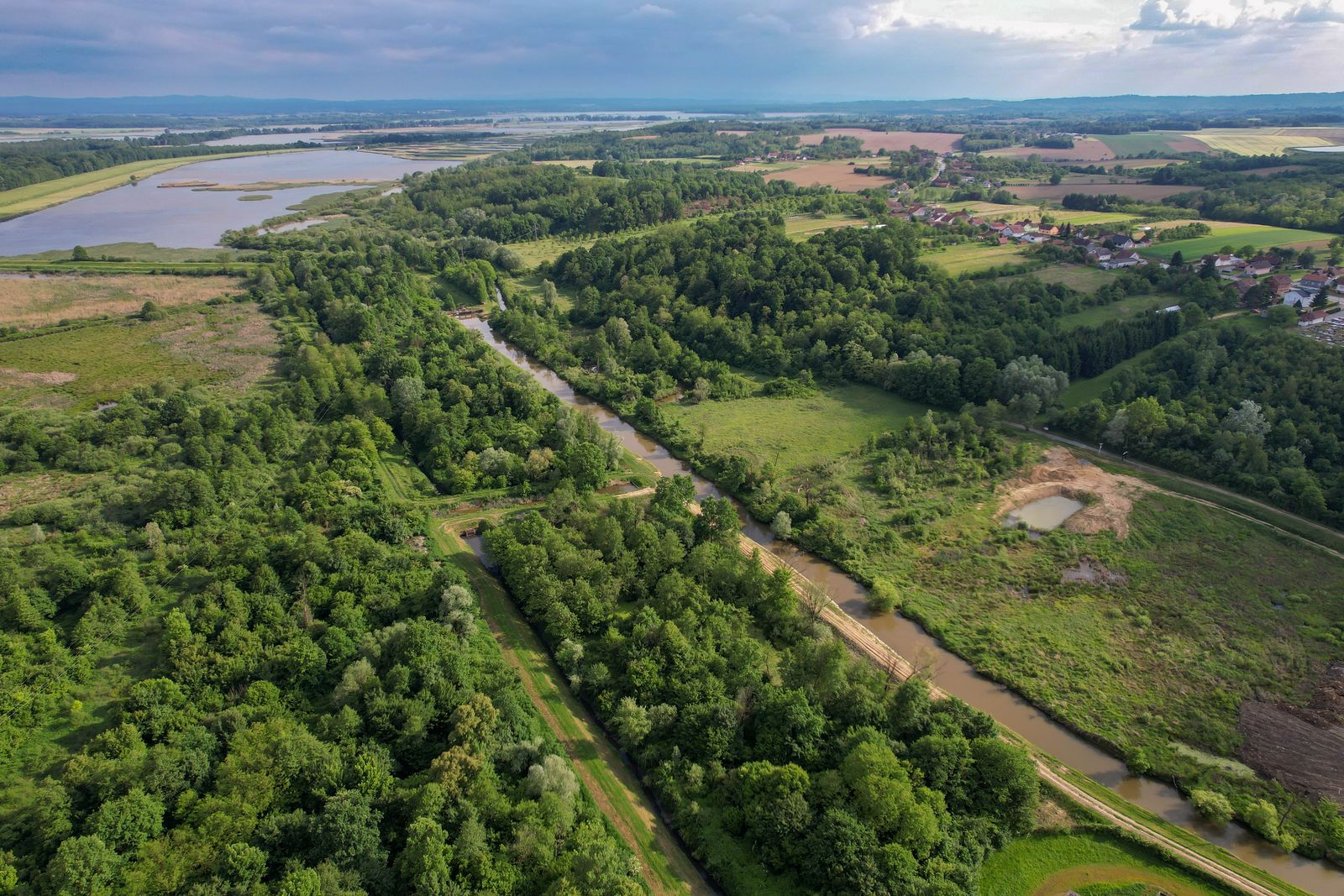Vista aérea de un amplio paisaje verde con un río, bosques y campos