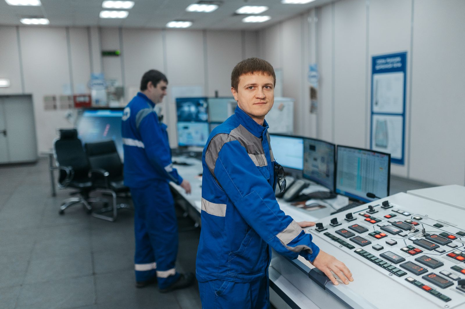 Técnicos en una sala de control monitorizando datos de energía en paneles industriales